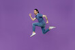 Full body side profile view young sporty man 20s wearing basic blue t-shirt jump high run fast in air hurrying up isolated on plain purple color background studio portrait. People lifestyle concept.