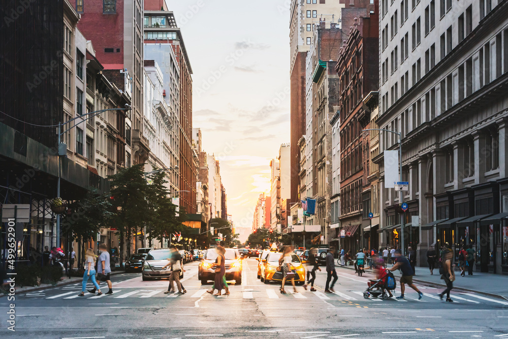 Crowds of people walking across the street at a busy intersection on ...