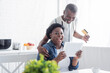 © LIGHTFIELD STUDIOS - senior african american man holding credit card near amazed wife with digital tablet.