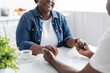 © LIGHTFIELD STUDIOS - cropped view of happy senior african american couple holding hands near cup of coffee.