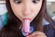 Little girl licking a whistle or melody pop