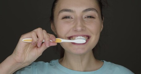 Sticker - Happy young woman brushing teeth on dark background