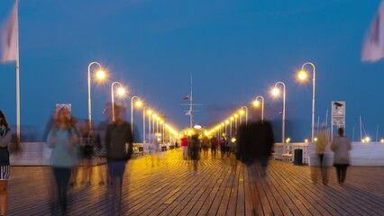 Canvas Print - Sopot, Poland. An evening time-lapse of a long wooden pier in Sopot, Poland, with a view of blurred people and a blue sky, panning video