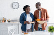 © LIGHTFIELD STUDIOS - happy senior african american man holding bowl with fruits near smiling wife.