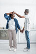 © LIGHTFIELD STUDIOS - full length of cheerful senior african american man holding hands with smiling wife while dancing in kitchen.