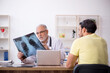 © Elnur - Young male doctor visiting old male doctor radiologist