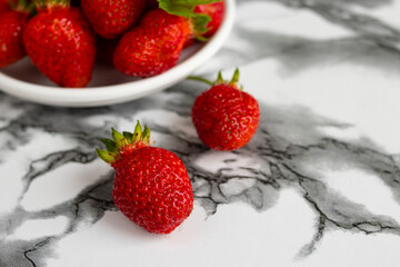 Fresh strawberries in bowl on marble background