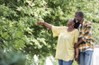 © LIGHTFIELD STUDIOS - happy senior african american woman pointing with hand near husband in park.
