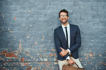 Wall Mural - Urban business. Cropped portrait of a handsome young businessman standing against a grey facebrick wall.