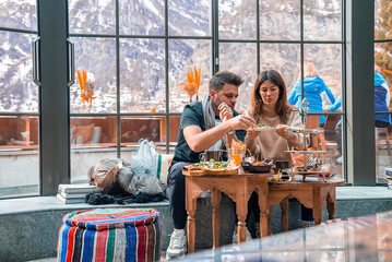 Wall Mural - Couple enjoying food together while sitting against window in luxurious resort