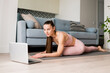 © tgordievskaya - Online Yoga classes. Woman doing virtual yoga from laptop at home for develop core strength, increase flexibility, improve posture, boost energy. Healthy living  concept