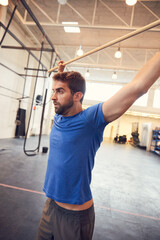 Wall Mural - You earn your body. Cropped shot of a handsome young man working out with a stick in the gym.