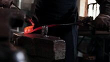 The Blacksmith Takes Out Heated Oblong Piece Of Metal And Begins To Bend In Using Forceps