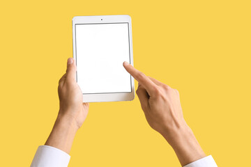 Male hands with modern tablet computer on color background