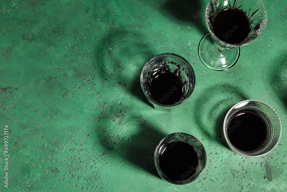 Different glasses with alcohol on green background