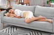 © Pixel-Shot - Young barefoot woman sleeping on sofa at home