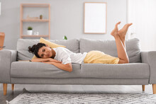 Young Barefoot Woman Lying On Sofa At Home