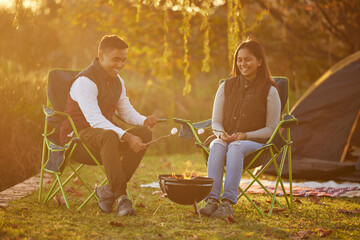 Poster - Lets make some smores. Shot of a couple roasting marshmellows while camping.