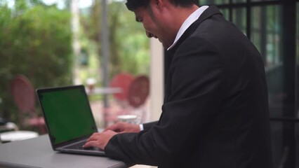 Poster - Close-up of green notebook computer screen with the fingers of a man in a business suit typing on a keyboard