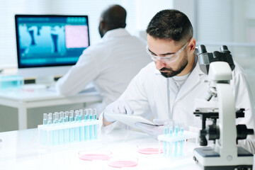 Aufkleber - Contemporary young male scientist in workwear using digital tablet while searching for online data about new biotechnologies