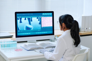 Aufkleber - Young contemporary virologist studying characteristics of new strain of coronavirus while sitting by workplace in front of computer screen