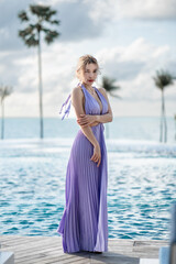 Sticker - Woman in purple dress posing by the pool with sea view.