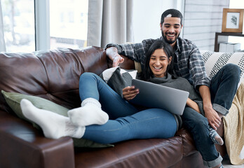 Poster - Romance isnt always a fancy date at a restaurant. Shot of a young couple using a laptop while relaxing on the sofa at home.
