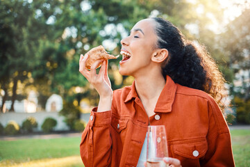 Canvas Print - A little snack and bubbles. Shot of a young woman eating pizza in a park.