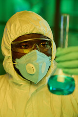 Aufkleber - Young black man in protective coveralls looking at big test tube with blue liquid while studying characteristics of new chemical substance