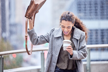 The rain got me. Shot of a young businesswoman carrying a coffee cup in the rain.