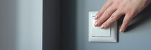 Female Hand Pressing Light Switch In Apartment Closeup