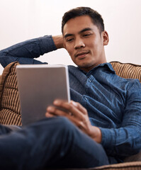 Sticker - Finally taking some time to relax. Shot of a young man using his digital tablet at home.