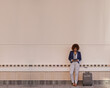 © Thurstan Hinrichsen/peopleimages.com - Getting some emails out of the way while she waits. A businesswoman using a digital tablet while standing with her luggage.