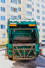 Fototapete - An automobile garbage truck collects garbage in residential areas of a modern city. Close-up of a car for collecting and transporting garbage.