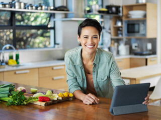 Poster - Ive found the perfect recipe. Portrait of a smiling young woman using a digital tablet while preparing a meal in her kitchen.