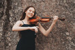 © Fotograf - Asian girl plays the violin on the background of a stone wall