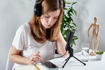 Wall Mural - Woman listening online course in headphones, distance education. Freelancer sitting at workplace and procrastinating. Lazy and distracted employee