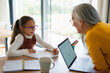 © Halfpoint - Small girl with senior grandmother doing homework at home.
