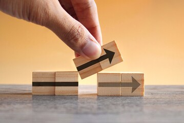hand holding wooden cubes with arrow icon. new strategy, changes, alternative path, and improvement