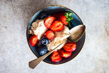 Overhead View Of A Bowl Of Vanilla Ice Cream With Fresh Blueberries And Strawberries
