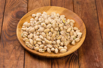 Wall Mural - Roasted salted pistachio nuts on wooden dish on rustic table