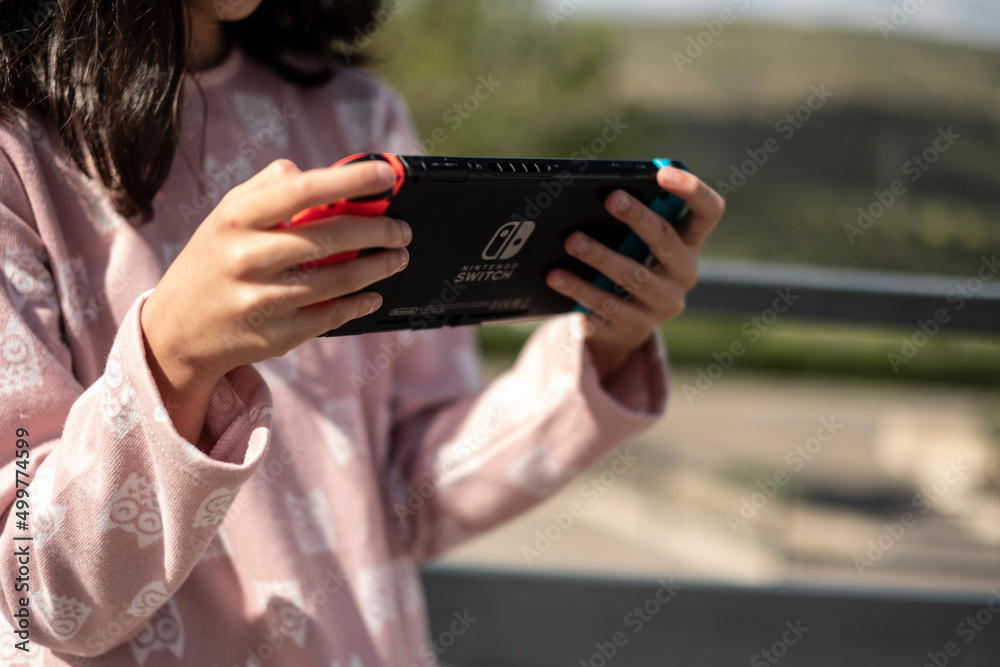 Foto Madrid Spain 13 April 2022 girl playing game on Nintendo Switch console in public park do Stock Adobe Stock