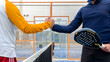 Male padel players handshake after win a padel match in blue paddel court indoor