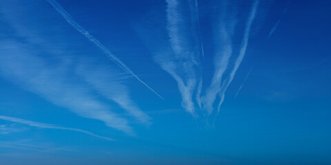 Wall Mural - Airplane contrail against blue sky. Jet plane condensation trail, clouds lines