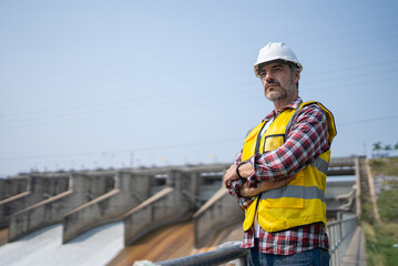 Portrait of engineer wearing yellow vest and white helmet Working day on a water dam with a hydroelectric power plant. Renewable energy systems, Sustainable energy concept