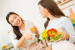 © anusak - Two beautiful Asian friends in sportswear cook salads in the kitchen.