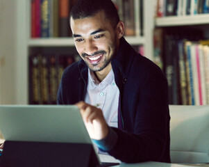Aufkleber - Hes got a great connection. Shot of a smiling young man working on a digital tablet in his home office in the early evening.