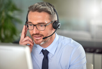 No dreams truly runs cold. Shot of a mature man using a headset and talking to clients while using his computer at work.