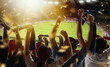 © master1305 - Rear view of football, soccer fans cheering their team with scarfs at crowded stadium at evening time. Concept of sport, support, competition. Out of focus effect