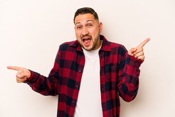 Young hispanic man isolated on white background pointing to different copy spaces, choosing one of them, showing with finger.